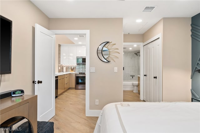 bedroom featuring light hardwood / wood-style flooring, connected bathroom, and a closet