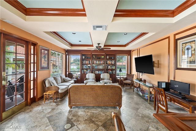 living room featuring a raised ceiling, ceiling fan, and a wealth of natural light