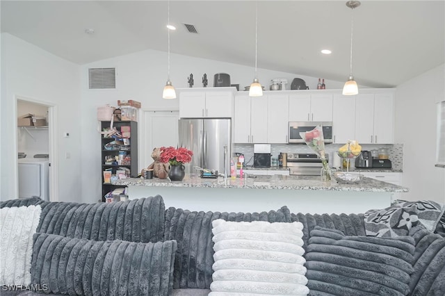 kitchen with decorative light fixtures, appliances with stainless steel finishes, washing machine and clothes dryer, and white cabinetry