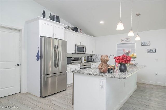 kitchen featuring white cabinetry, pendant lighting, stainless steel appliances, lofted ceiling, and a center island with sink