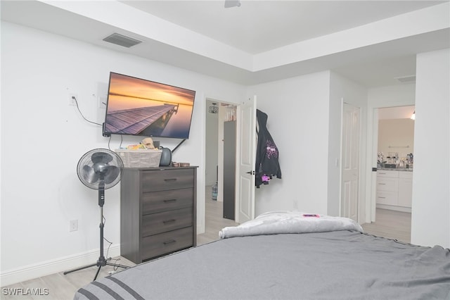 bedroom featuring light wood-type flooring and ensuite bath