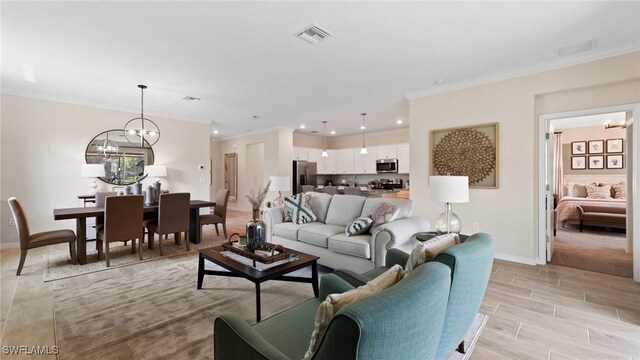 living room with an inviting chandelier, ornamental molding, baseboards, and visible vents