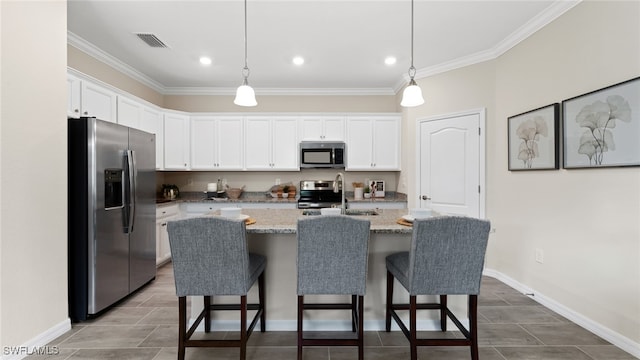 kitchen featuring white cabinets, a kitchen island with sink, appliances with stainless steel finishes, and decorative light fixtures