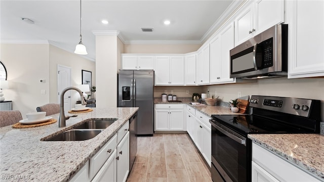 kitchen featuring light stone counters, white cabinets, hanging light fixtures, sink, and appliances with stainless steel finishes