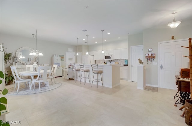 kitchen featuring pendant lighting, white appliances, a kitchen island, white cabinetry, and decorative backsplash