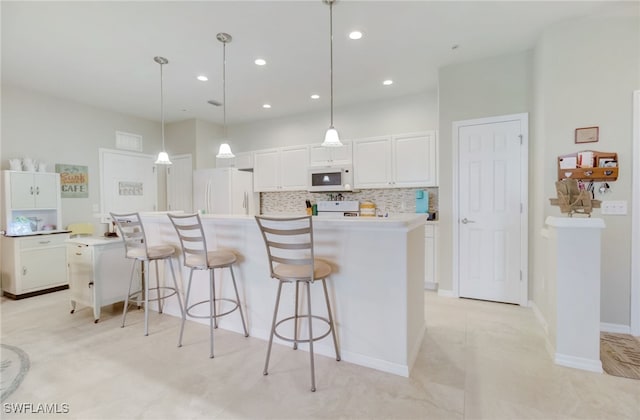 kitchen with pendant lighting, white appliances, white cabinetry, a center island, and decorative backsplash