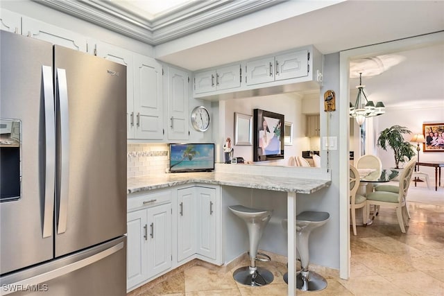 kitchen with kitchen peninsula, stainless steel fridge, tasteful backsplash, light stone counters, and white cabinets