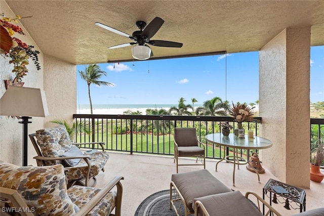 view of patio featuring ceiling fan, a water view, and a balcony