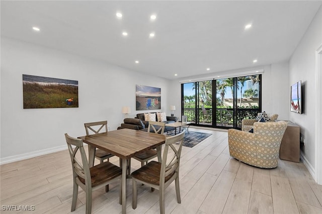 dining room with light hardwood / wood-style flooring and a wall of windows