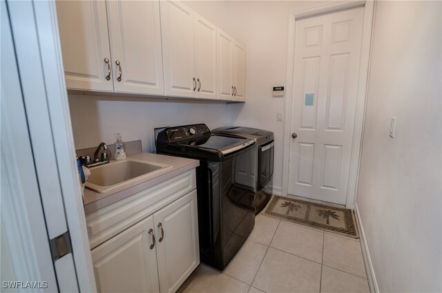 laundry area featuring washer and clothes dryer, sink, light tile patterned floors, and cabinets