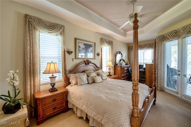 carpeted bedroom with ceiling fan, a tray ceiling, multiple windows, and access to outside