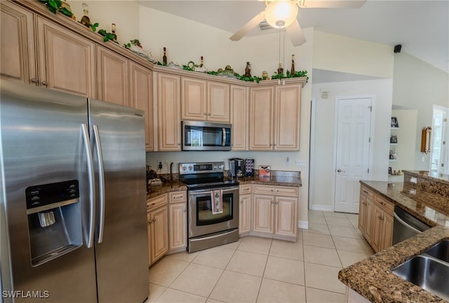 kitchen featuring appliances with stainless steel finishes, dark stone countertops, vaulted ceiling, light tile patterned floors, and ceiling fan