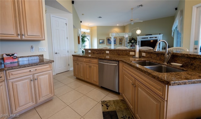 kitchen with ceiling fan, light tile patterned floors, sink, stainless steel dishwasher, and dark stone countertops