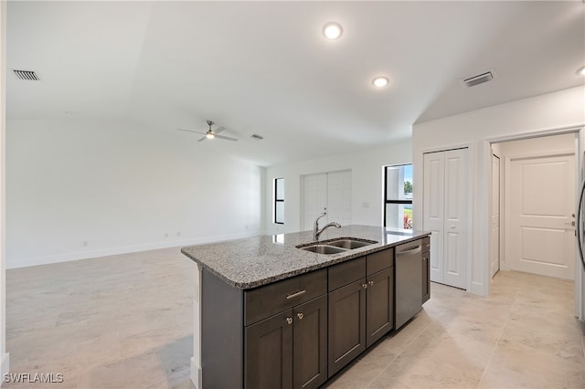 kitchen featuring light stone countertops, sink, dishwasher, dark brown cabinets, and a center island with sink