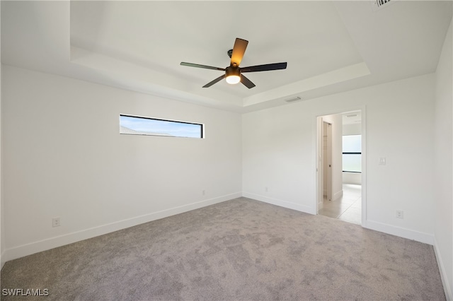 unfurnished room with light carpet, a tray ceiling, and ceiling fan