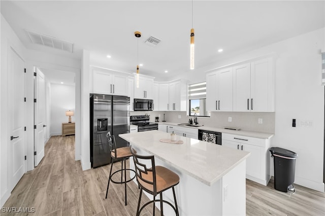 kitchen with white cabinetry, light wood-type flooring, black appliances, pendant lighting, and a center island