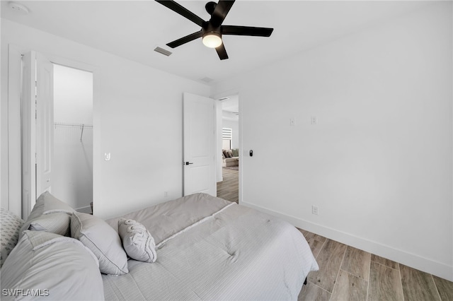 bedroom with a spacious closet, light hardwood / wood-style flooring, a closet, and ceiling fan