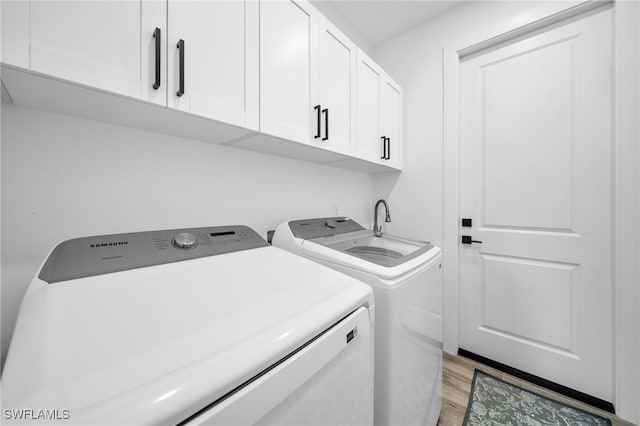 laundry room featuring light hardwood / wood-style floors, separate washer and dryer, and cabinets