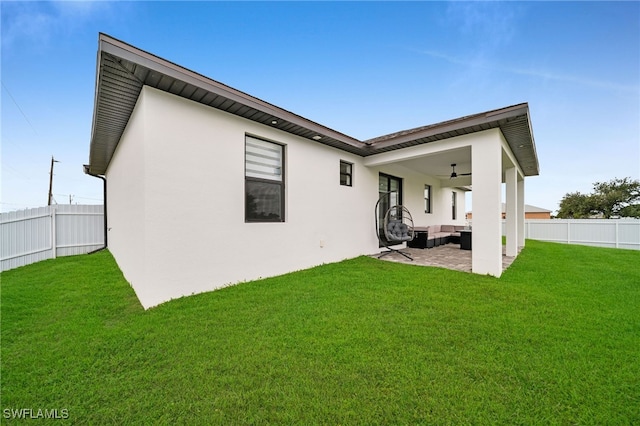 back of house with an outdoor living space, a yard, a patio area, and ceiling fan