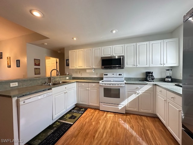 kitchen featuring sink, kitchen peninsula, white appliances, and white cabinetry