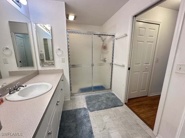 bathroom with vanity, hardwood / wood-style floors, and a shower with door