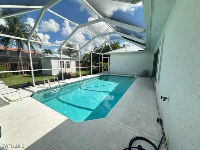 view of swimming pool featuring a patio, glass enclosure, and a storage unit