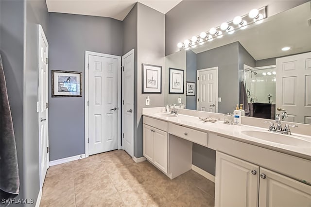 bathroom with a shower with door, vanity, and tile patterned flooring