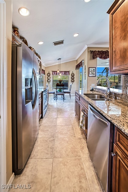 kitchen with appliances with stainless steel finishes, light tile patterned flooring, sink, hanging light fixtures, and vaulted ceiling