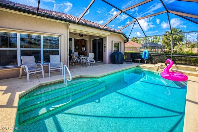 view of swimming pool featuring a patio area, glass enclosure, and ceiling fan