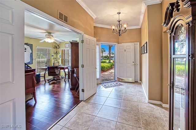 foyer entrance featuring a towering ceiling, ornamental molding, light tile patterned floors, and ceiling fan with notable chandelier