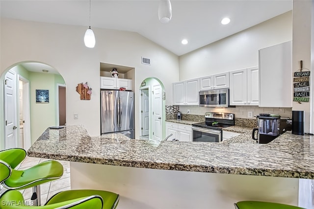 kitchen featuring tasteful backsplash, white cabinets, stainless steel appliances, lofted ceiling, and decorative light fixtures