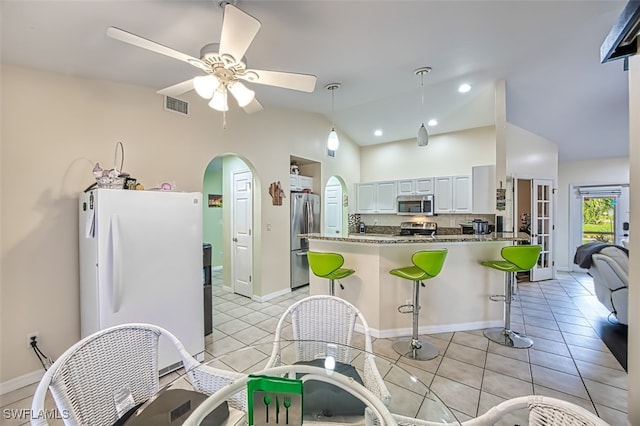 kitchen featuring light tile patterned flooring, white cabinets, vaulted ceiling, appliances with stainless steel finishes, and ceiling fan