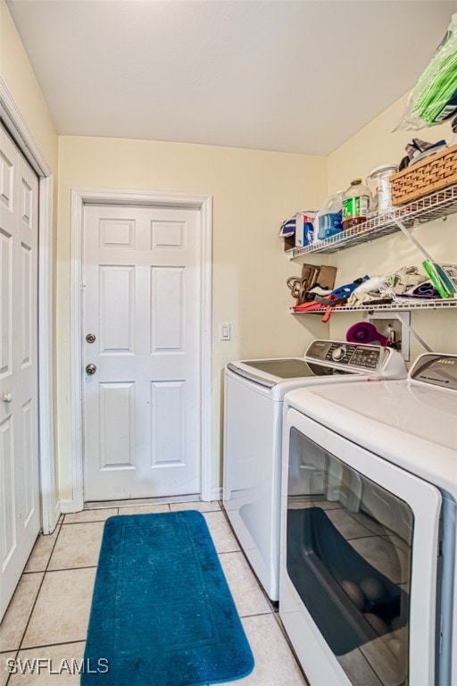 laundry room with light tile patterned flooring and washer and clothes dryer