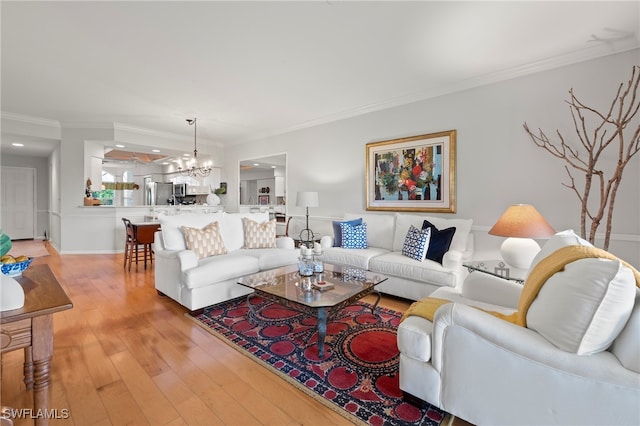 living room with light hardwood / wood-style flooring, a notable chandelier, and crown molding