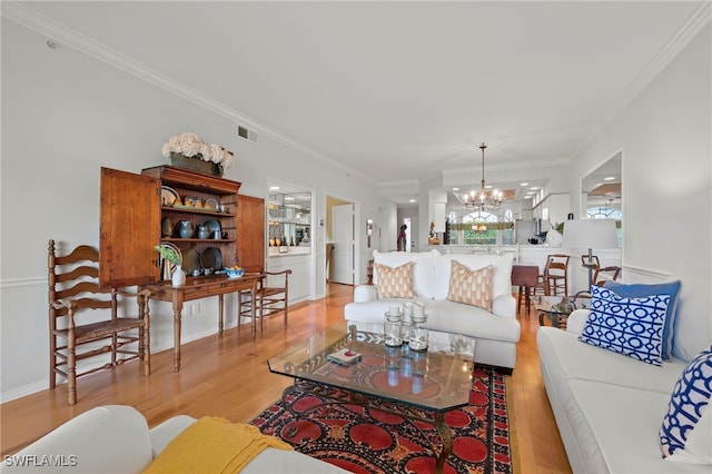 living room with crown molding, light hardwood / wood-style flooring, and a notable chandelier