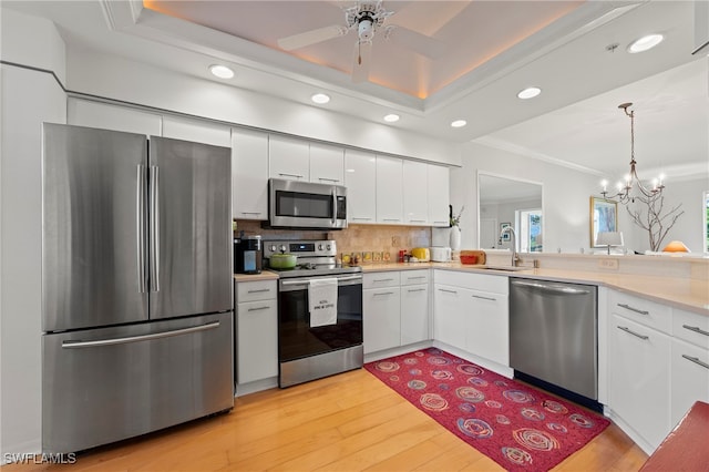 kitchen with light hardwood / wood-style flooring, stainless steel appliances, white cabinets, and ceiling fan with notable chandelier