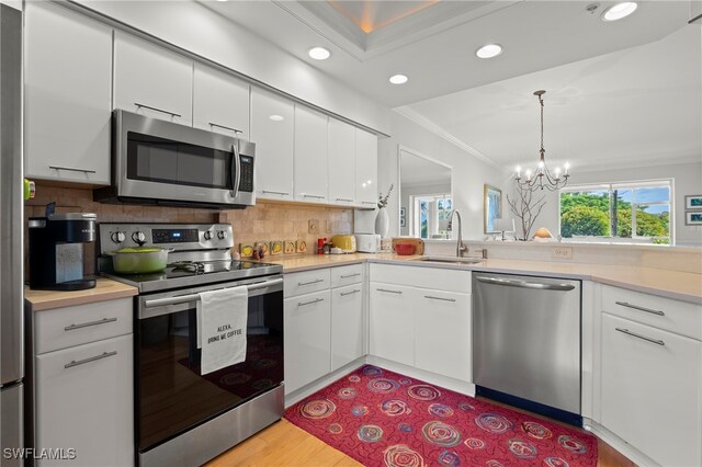 kitchen featuring white cabinets, a chandelier, appliances with stainless steel finishes, and sink