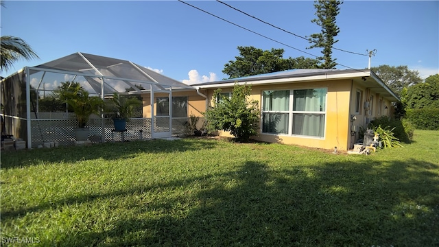 rear view of house with a lawn and a lanai