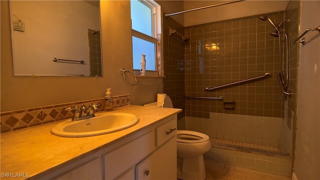 bathroom featuring a tile shower, vanity, and toilet