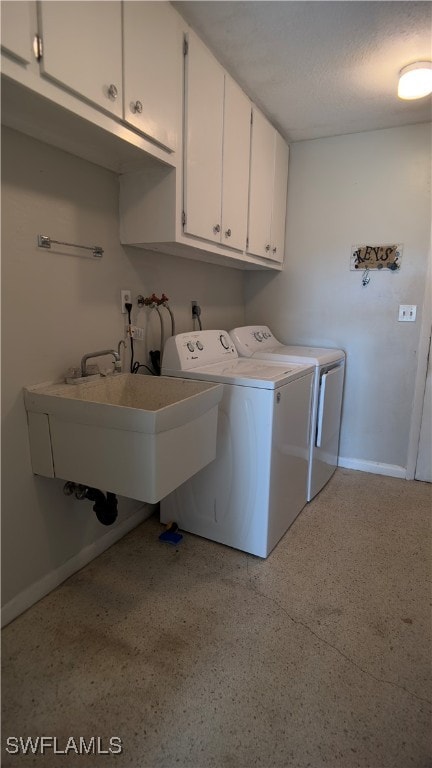 clothes washing area with a textured ceiling, sink, independent washer and dryer, and cabinets