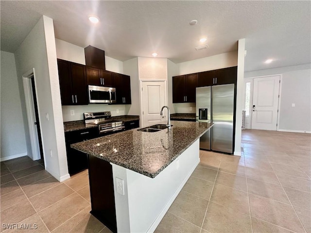 kitchen featuring appliances with stainless steel finishes, sink, light tile patterned floors, and a kitchen island with sink