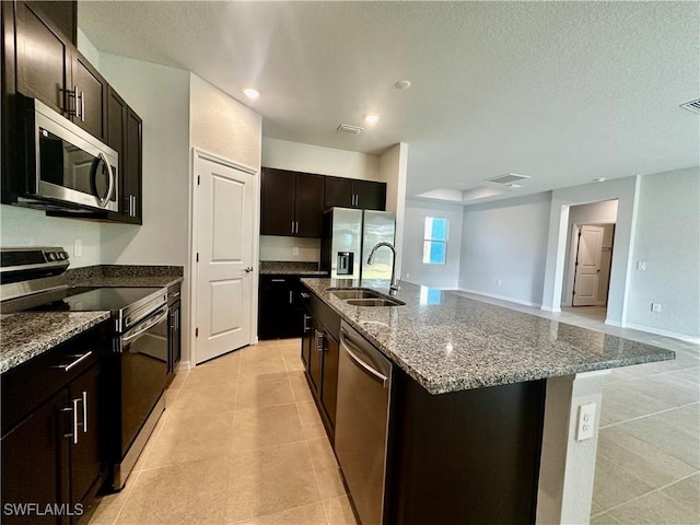 kitchen with dark brown cabinetry, stainless steel appliances, sink, and an island with sink