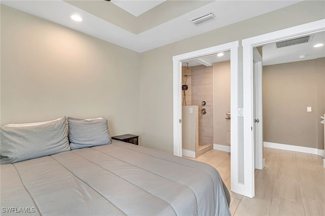 bedroom with connected bathroom and light wood-type flooring