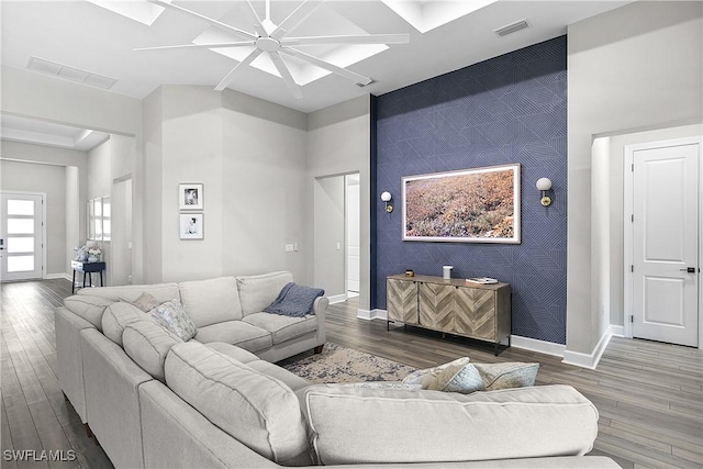 living room with hardwood / wood-style floors, a towering ceiling, and ceiling fan