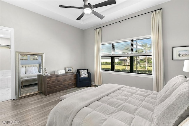 bedroom featuring ensuite bath, light hardwood / wood-style flooring, and ceiling fan