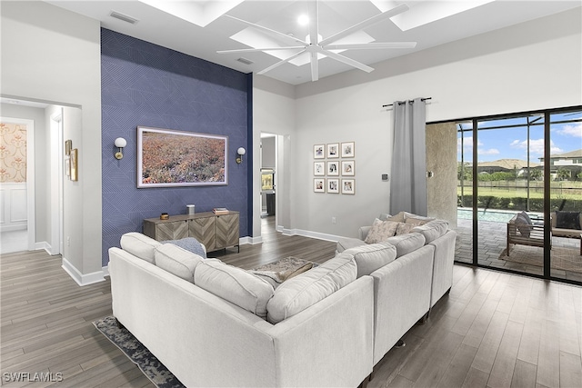 living room featuring ceiling fan, a towering ceiling, and dark hardwood / wood-style floors