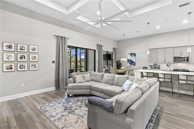 living room featuring ceiling fan, light wood-type flooring, and a towering ceiling