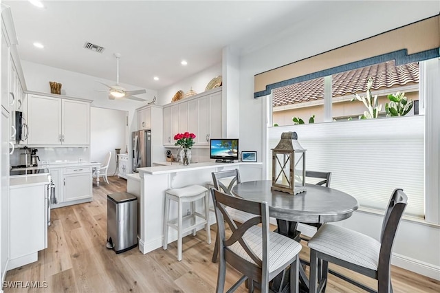 kitchen featuring kitchen peninsula, stainless steel appliances, ceiling fan, light hardwood / wood-style flooring, and white cabinetry