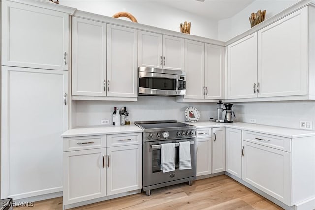 kitchen with white cabinetry, appliances with stainless steel finishes, and light hardwood / wood-style flooring