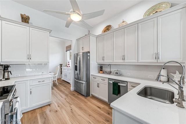 kitchen with stainless steel appliances, ceiling fan, sink, light hardwood / wood-style flooring, and white cabinets